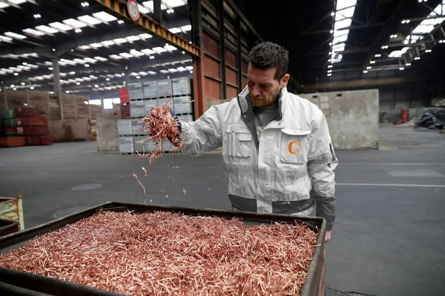 Worker inspecting a bin of chopped copper